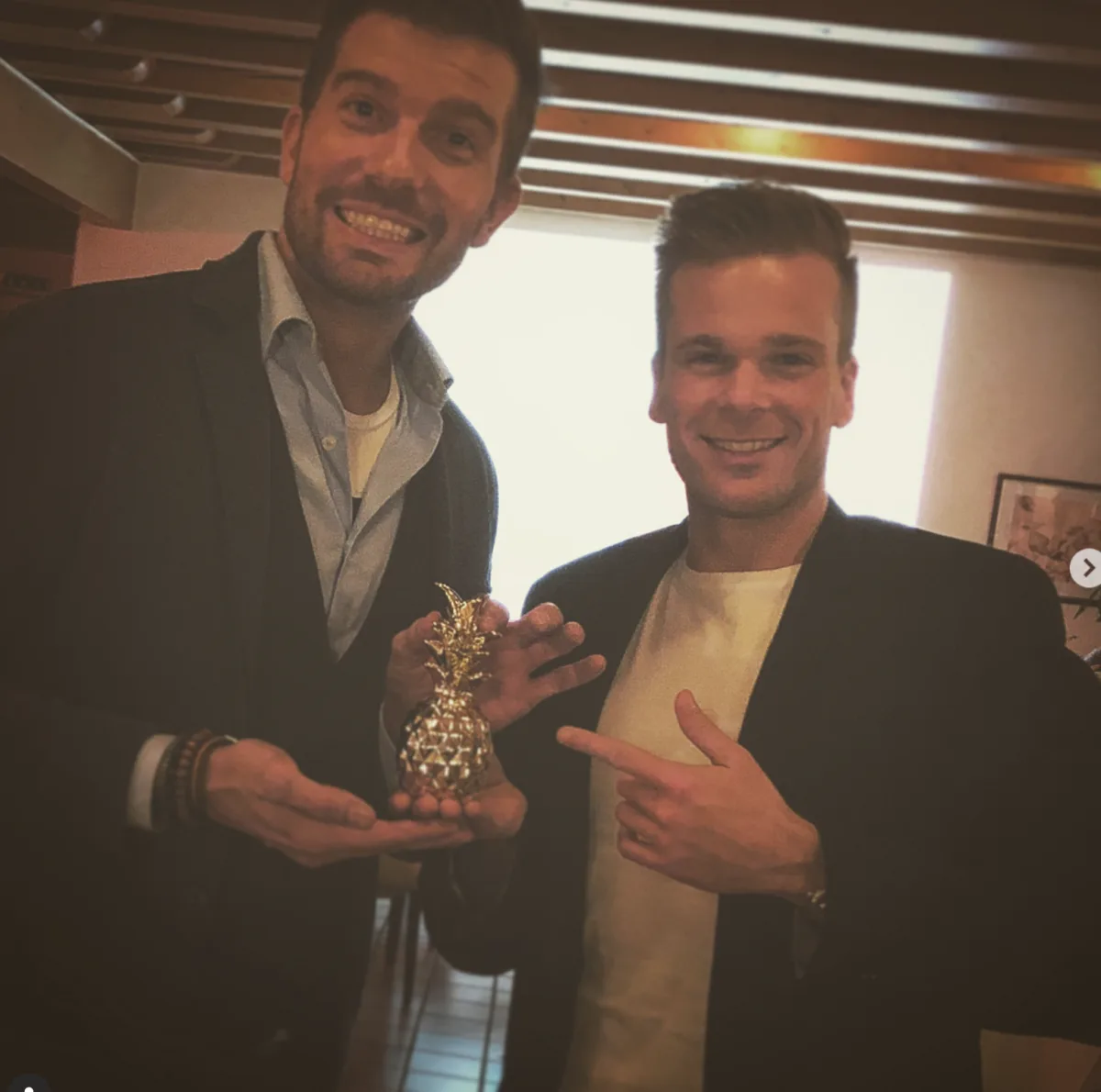 Zwei Männer mit einer goldenen Ananas